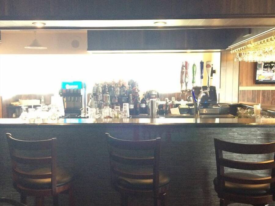 A bar area with a counter, bar stools, and a television screen.