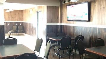 A restaurant with wooden walls, multiple tables and chairs, and a TV mounted on the wall.