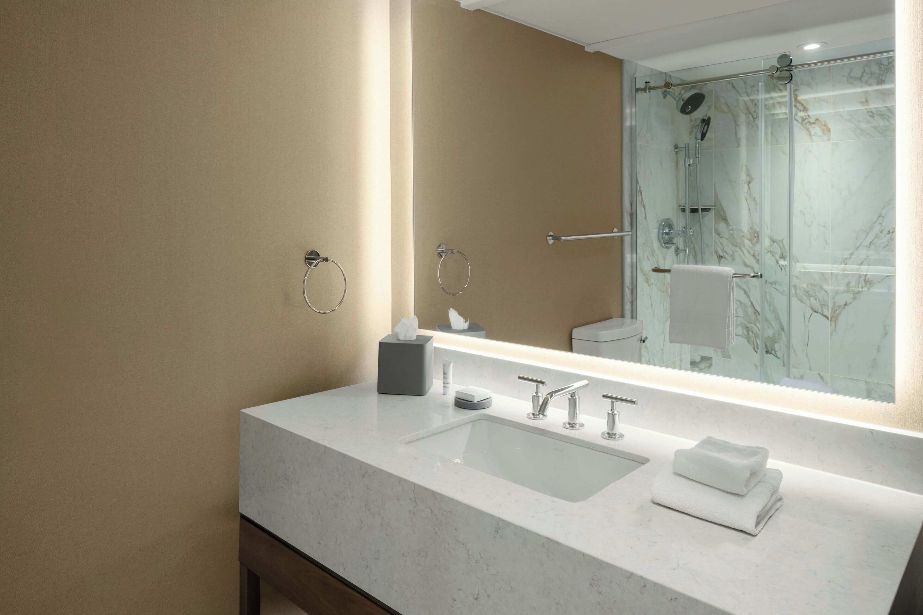 A modern bathroom with a large mirror, a sink, and a shower.