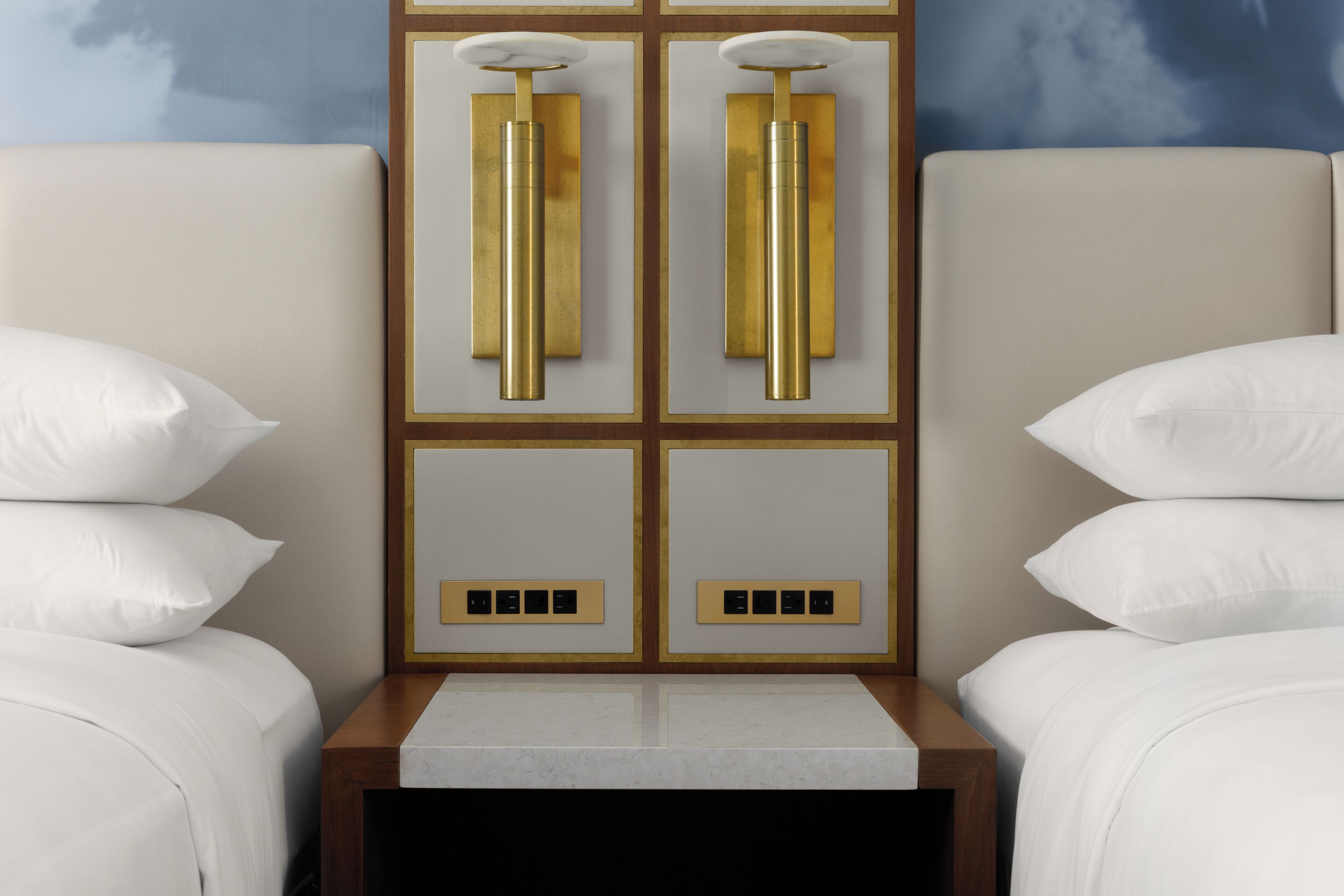 Una habitación de hotel con una cama, una mesita de noche y una lámpara fijada en la pared.
