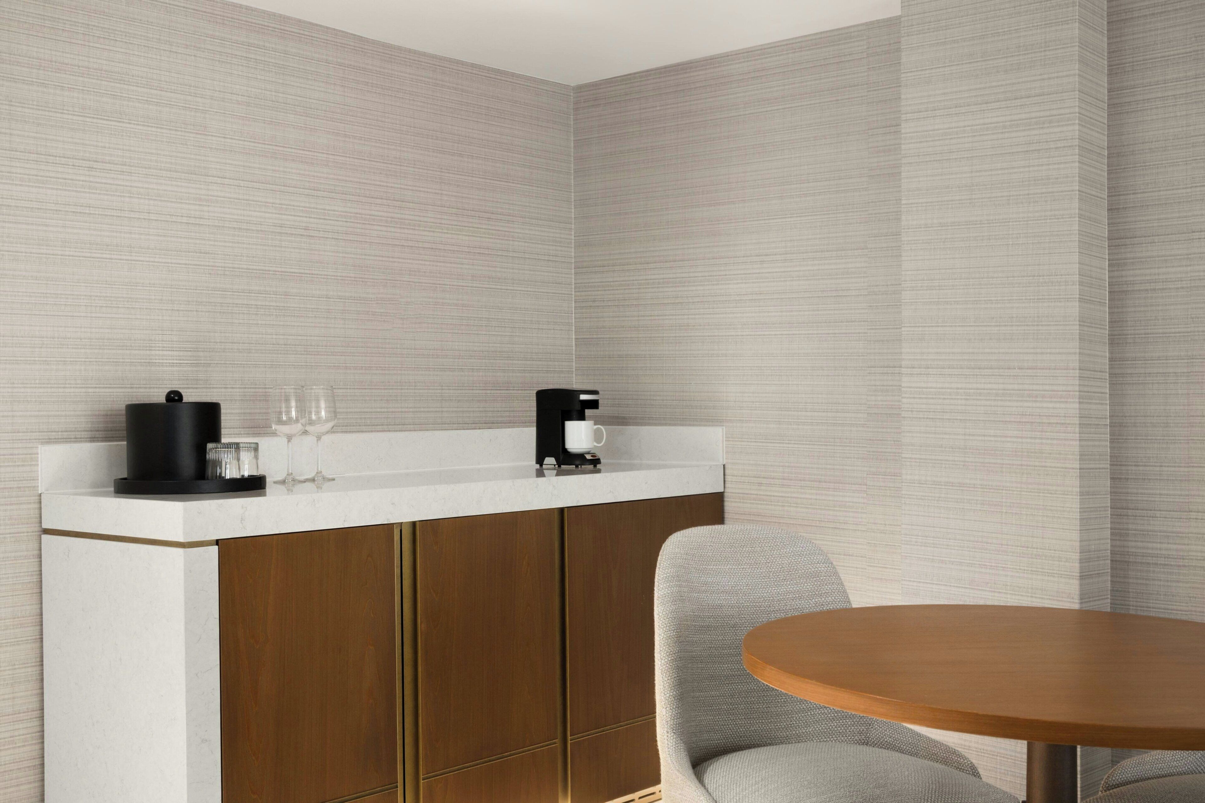 A modern kitchen with a white countertop, wooden cabinets, and a round dining table.