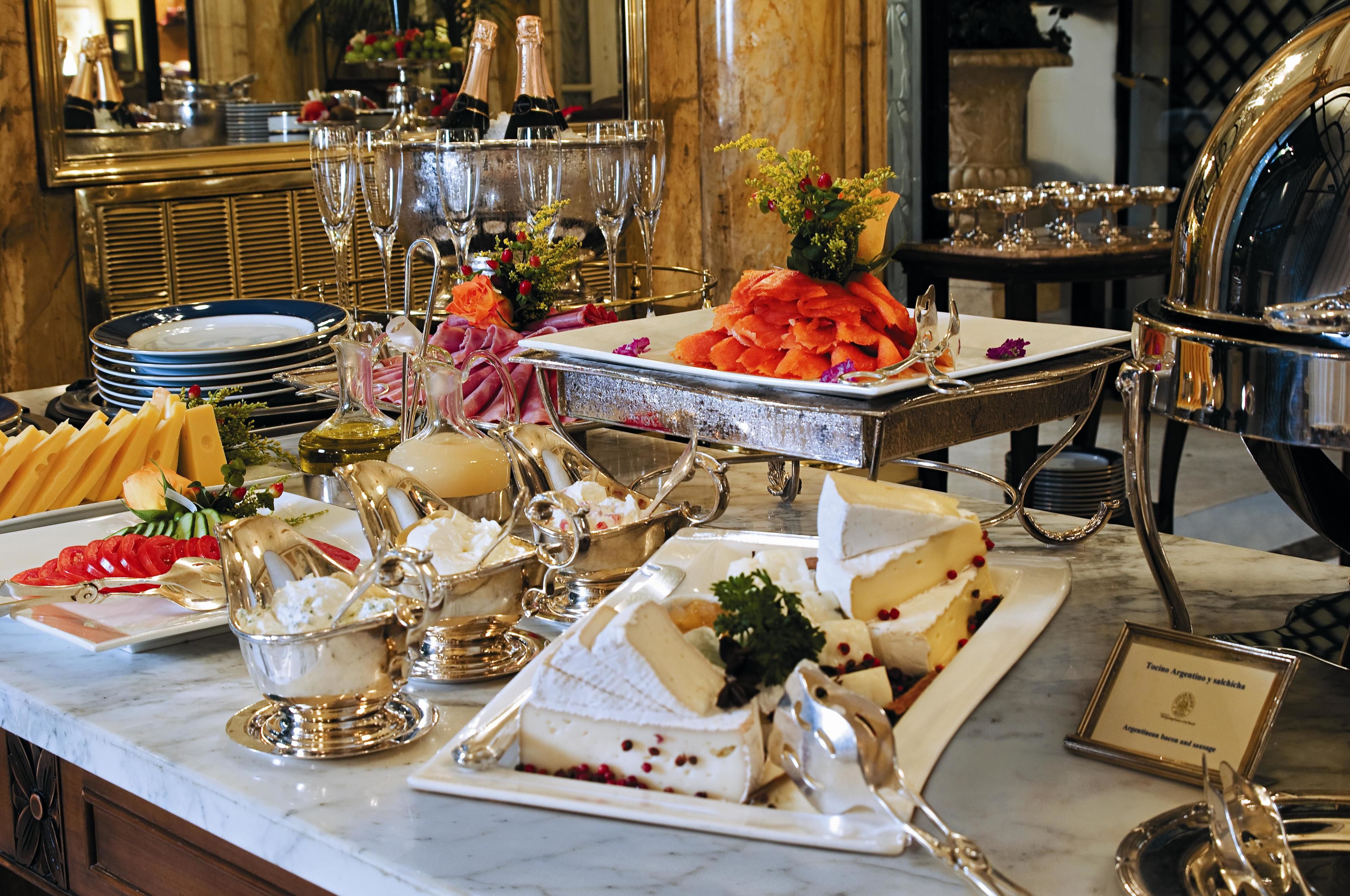 Une table de buffet avec différents fromages, des fruits et un gâteau.