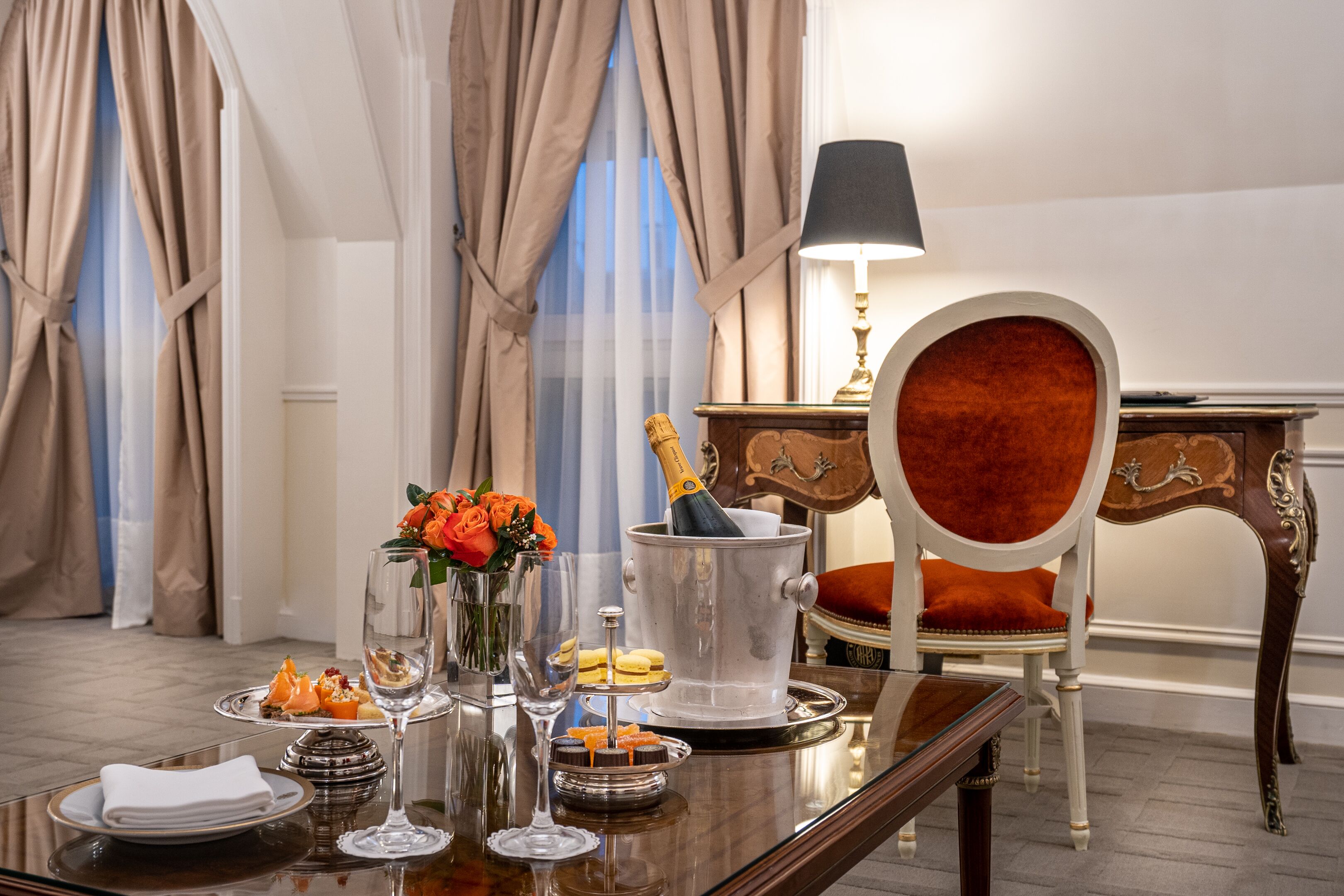 A dining table set with a champagne bottle, a vase of flowers, and various desserts.