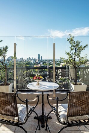A rooftop terrace with a table and chairs, a vase of flowers, and a city view. - Alvear Palace Hotel (Buenos Aires)