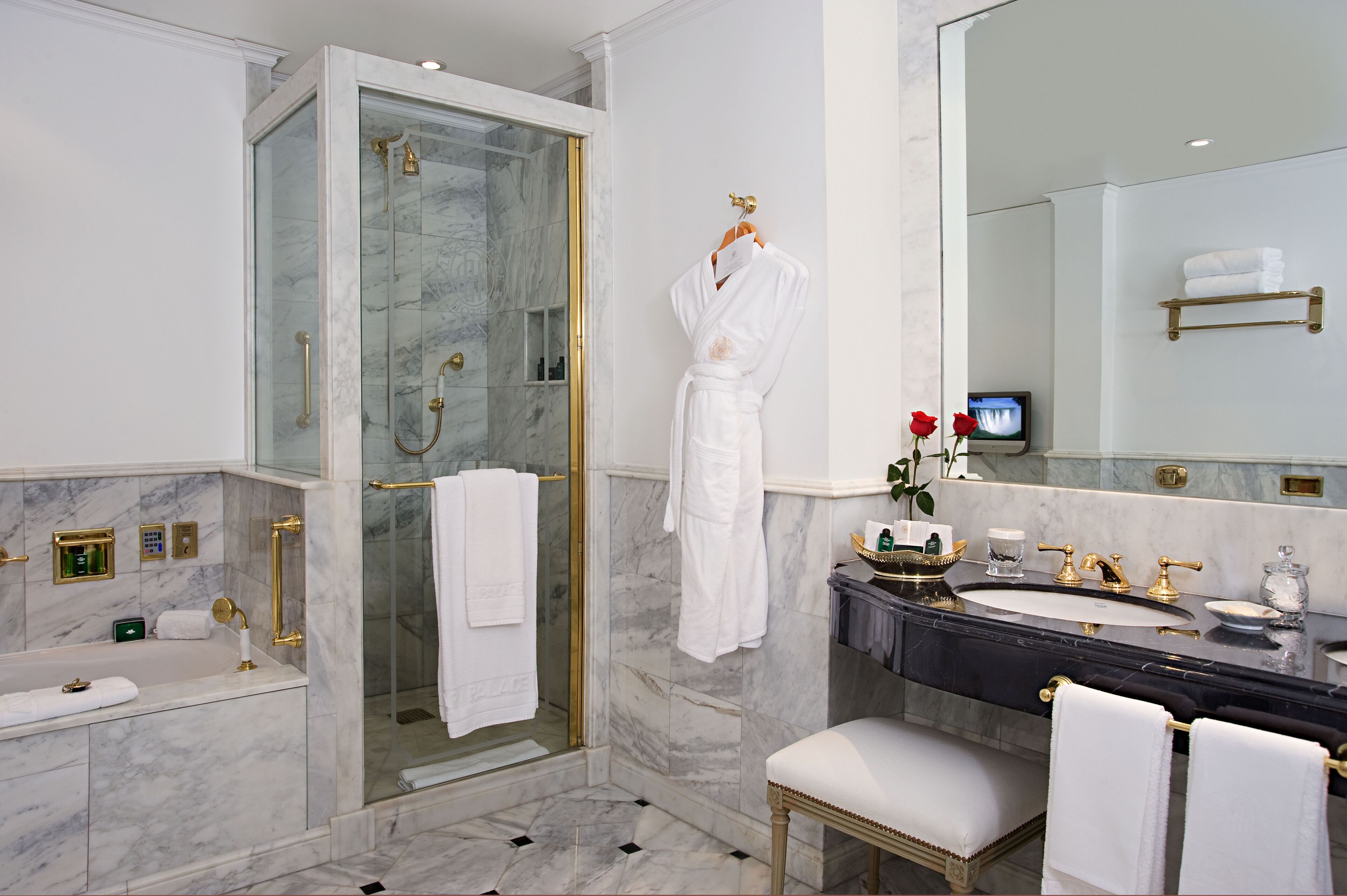 Een luxe badkamer met een douchecabine van glas, een wastafel met een zwart aanrechtblad en een grote spiegel.