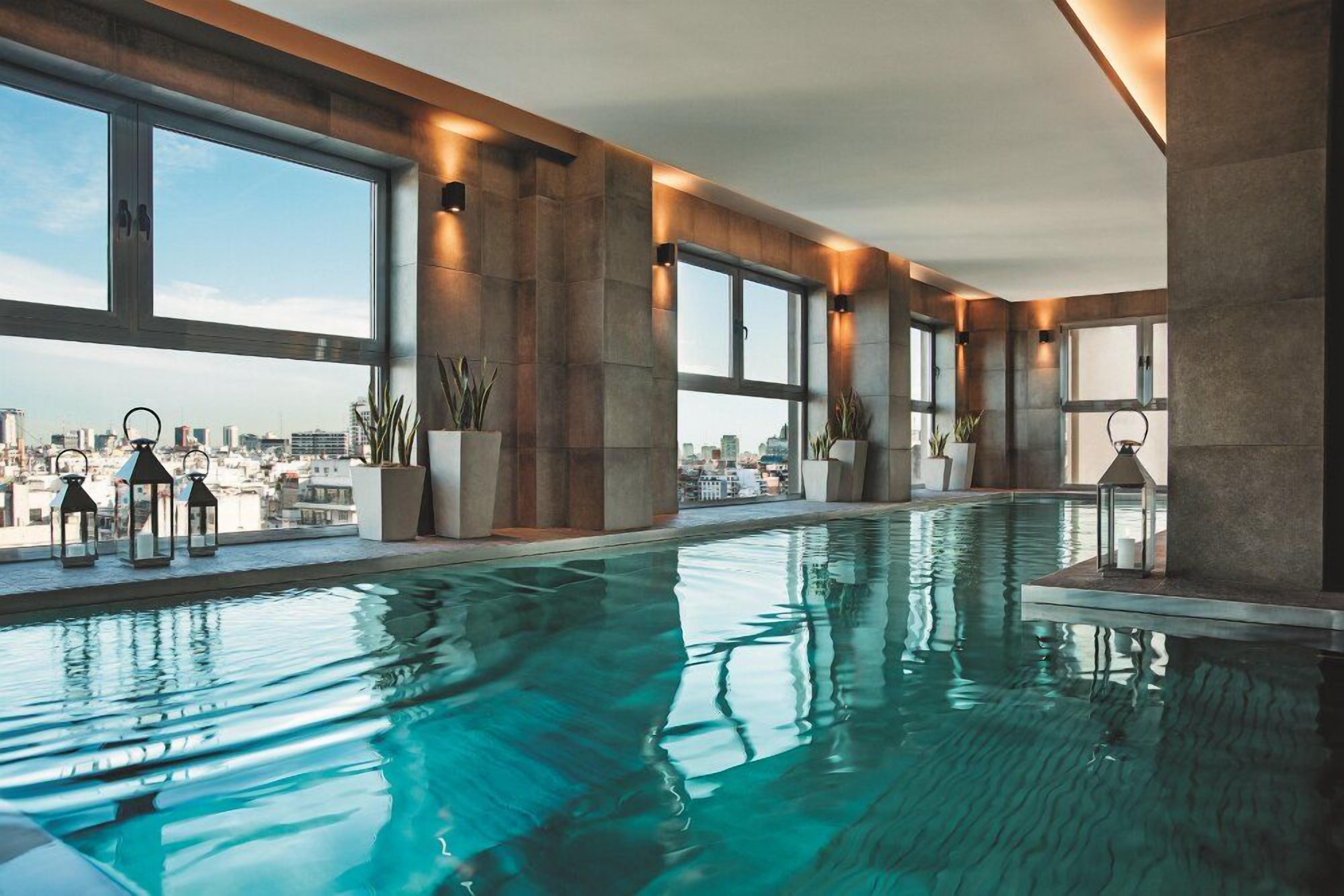 Una piscina interior con amplios ventanales y vistas a la ciudad.