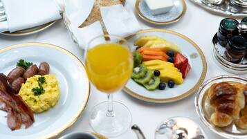 A breakfast setting with plates of eggs, bacon, toast, and fruit.