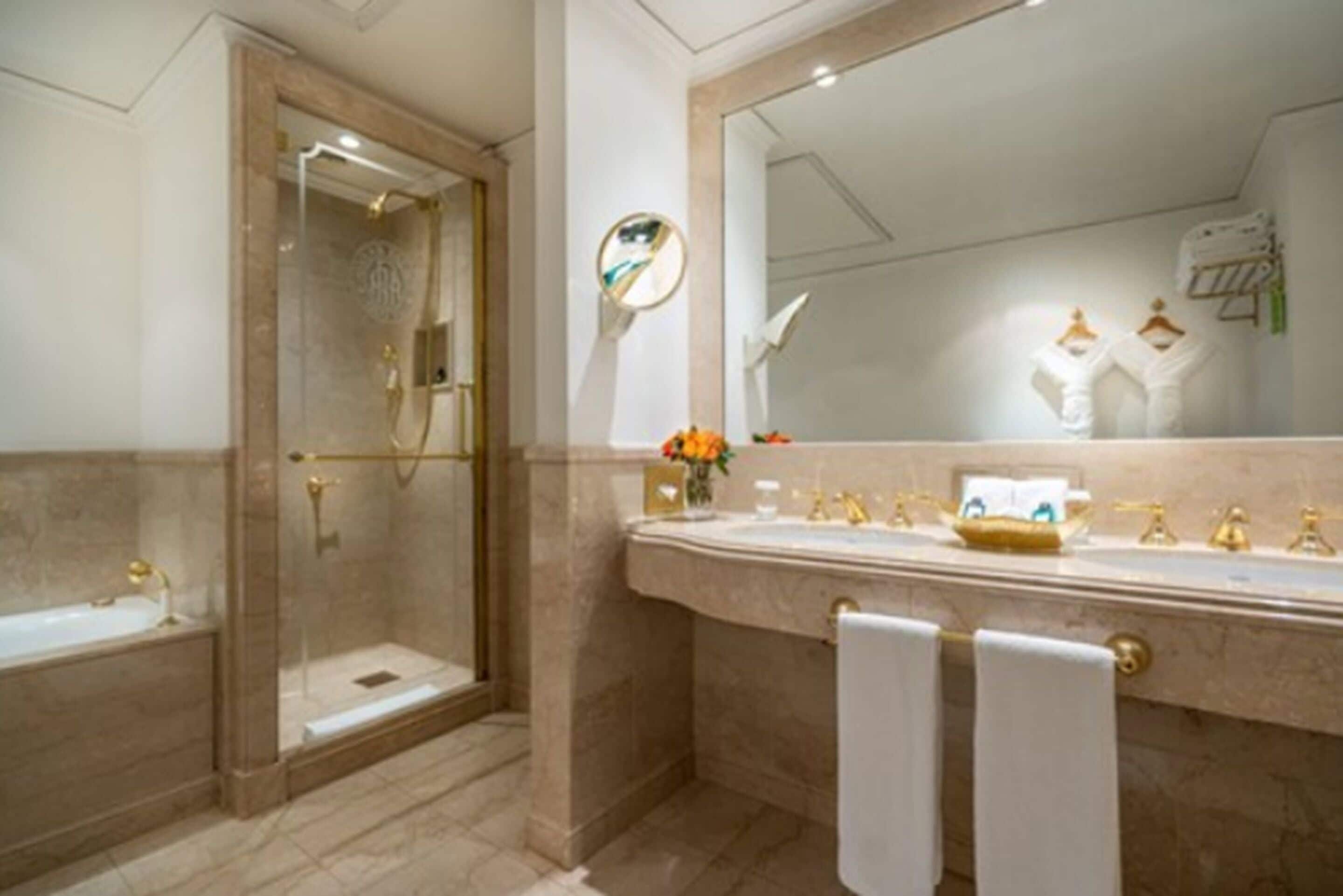 A bathroom with a bathtub, a shower, and a vanity with a mirror.