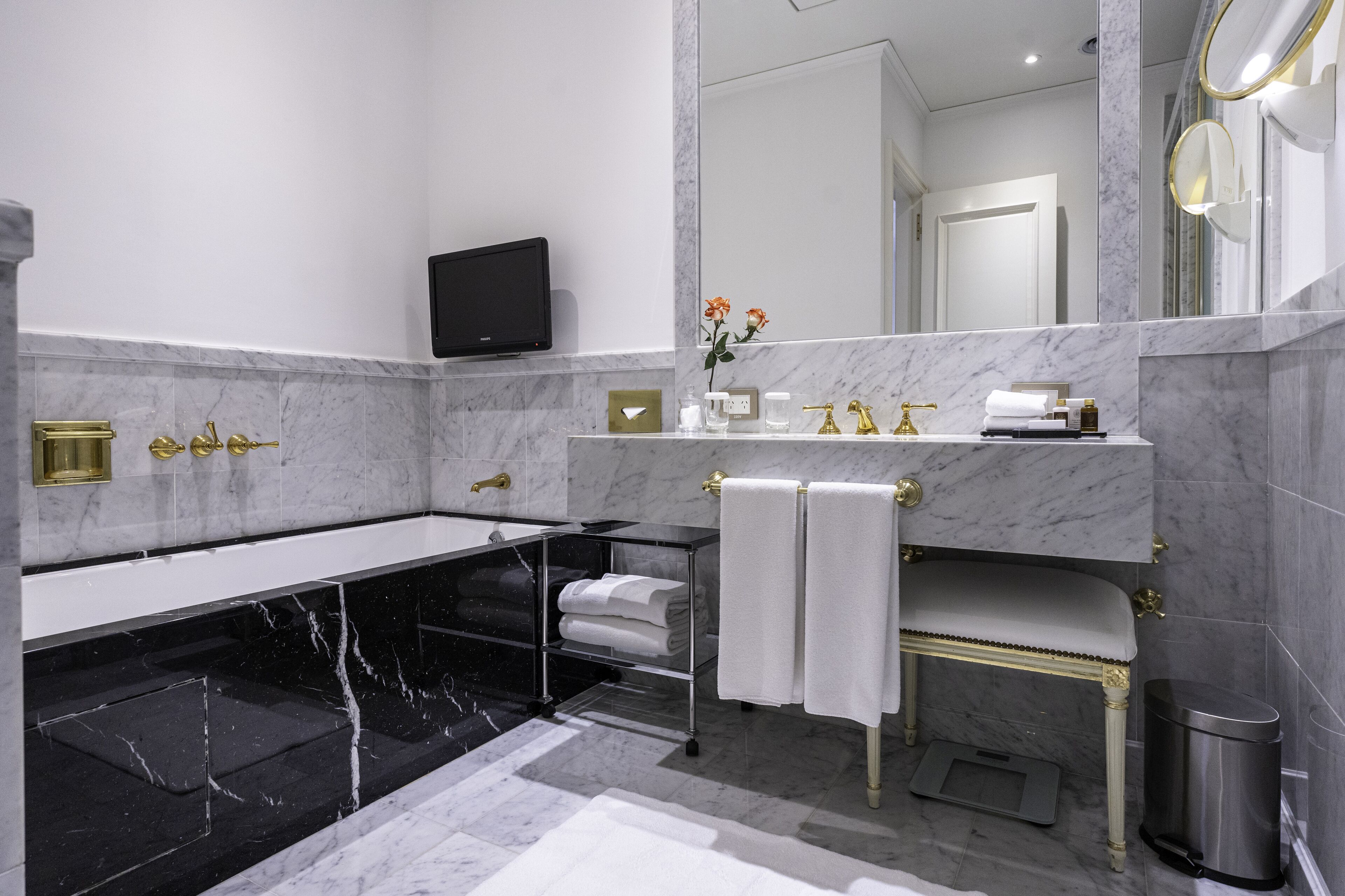 A modern bathroom with a marble vanity, a bathtub, and a large mirror.