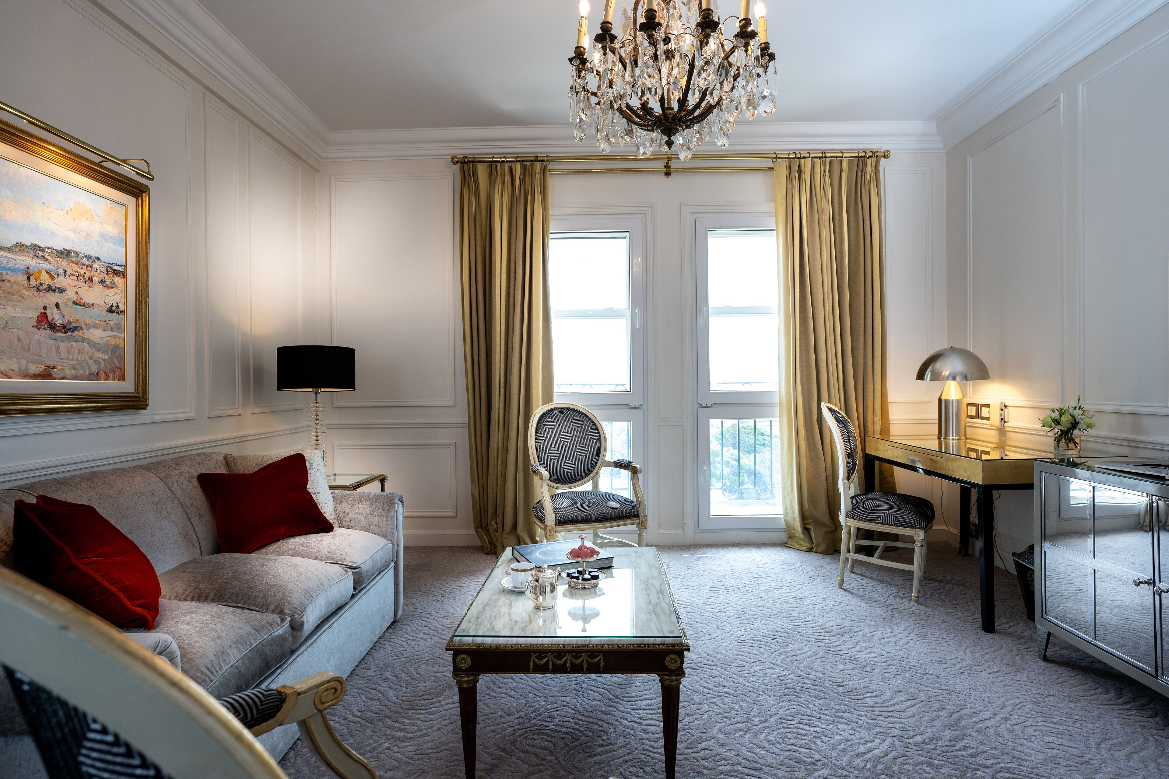 Una habitación bien iluminada con sofá, mesa, silla, escritorio y candelabro.