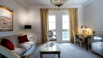 Una habitación bien iluminada con sofá, mesa, silla, escritorio y candelabro.