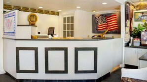 A reception area with a counter, a clock, a window, and an American flag.