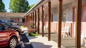 A motel with a covered parking area, American flags, and a brick facade.