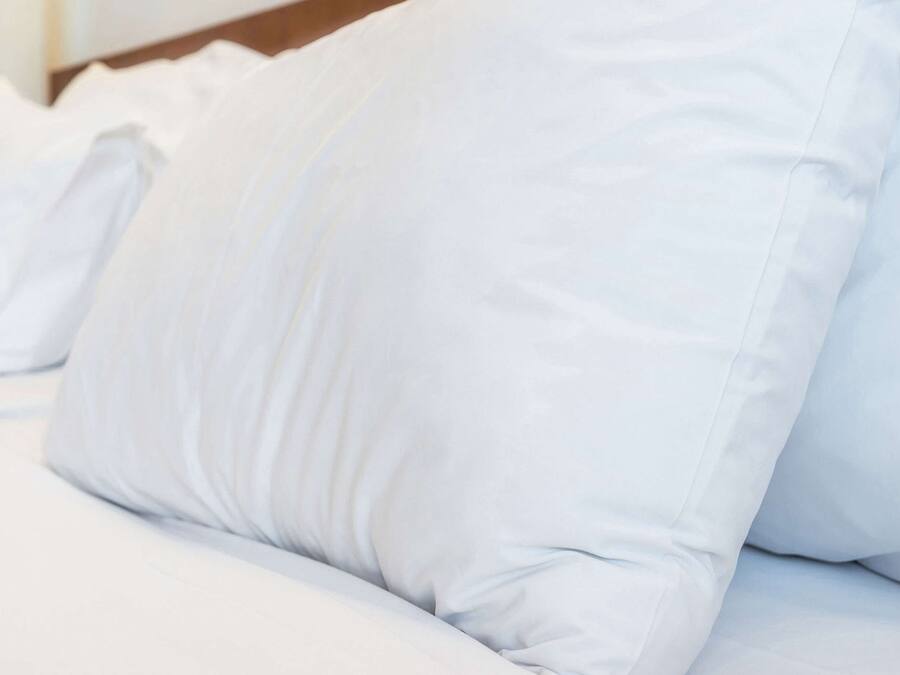 A bed with white bedding and pillows.