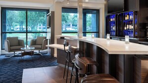 Un espace bar moderne doté d’un comptoir incurvé, de tabourets de bar et d’un présentoir à vin.
