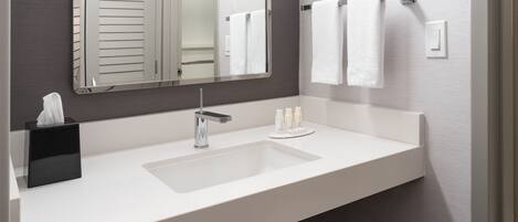 Un baño moderno con un lavamanos blanco, un espejo y un perchero para toallas.