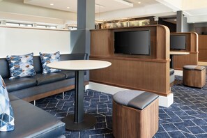 Un espace de détente moderne comprenant un canapé, une table ronde et un écran de télévision.