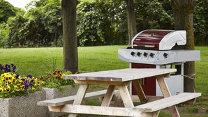 A picnic table with a barbecue grill in a park. - Comfort Inn Winnipeg Airport (Winnipeg)