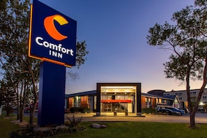 A Comfort Inn hotel with a prominent sign, a modern building entrance, and a parking lot.