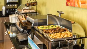 A buffet setup with various food items, including meats and potatoes, and a coffee station in the background.