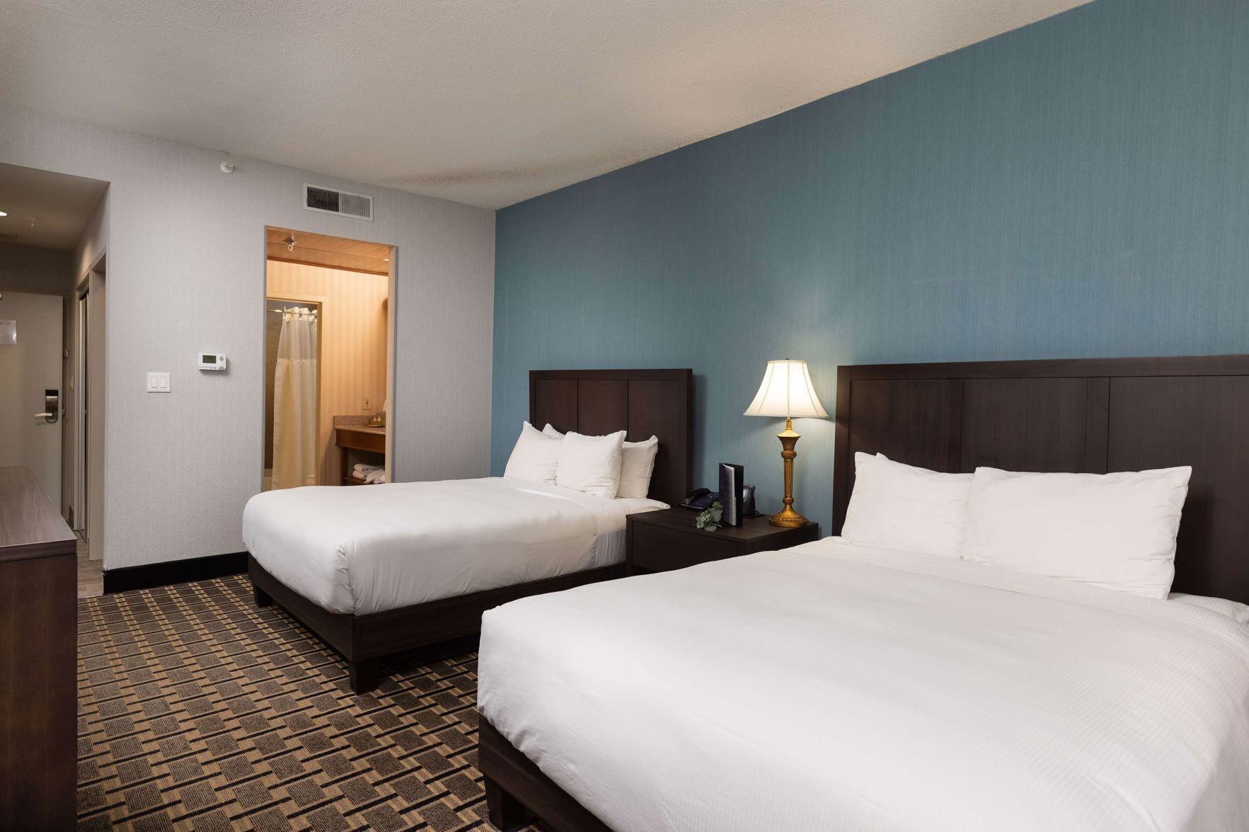 أغطية فراش متميزة وخزنة داخل الغرفة ومكتب وستائر تعتيم