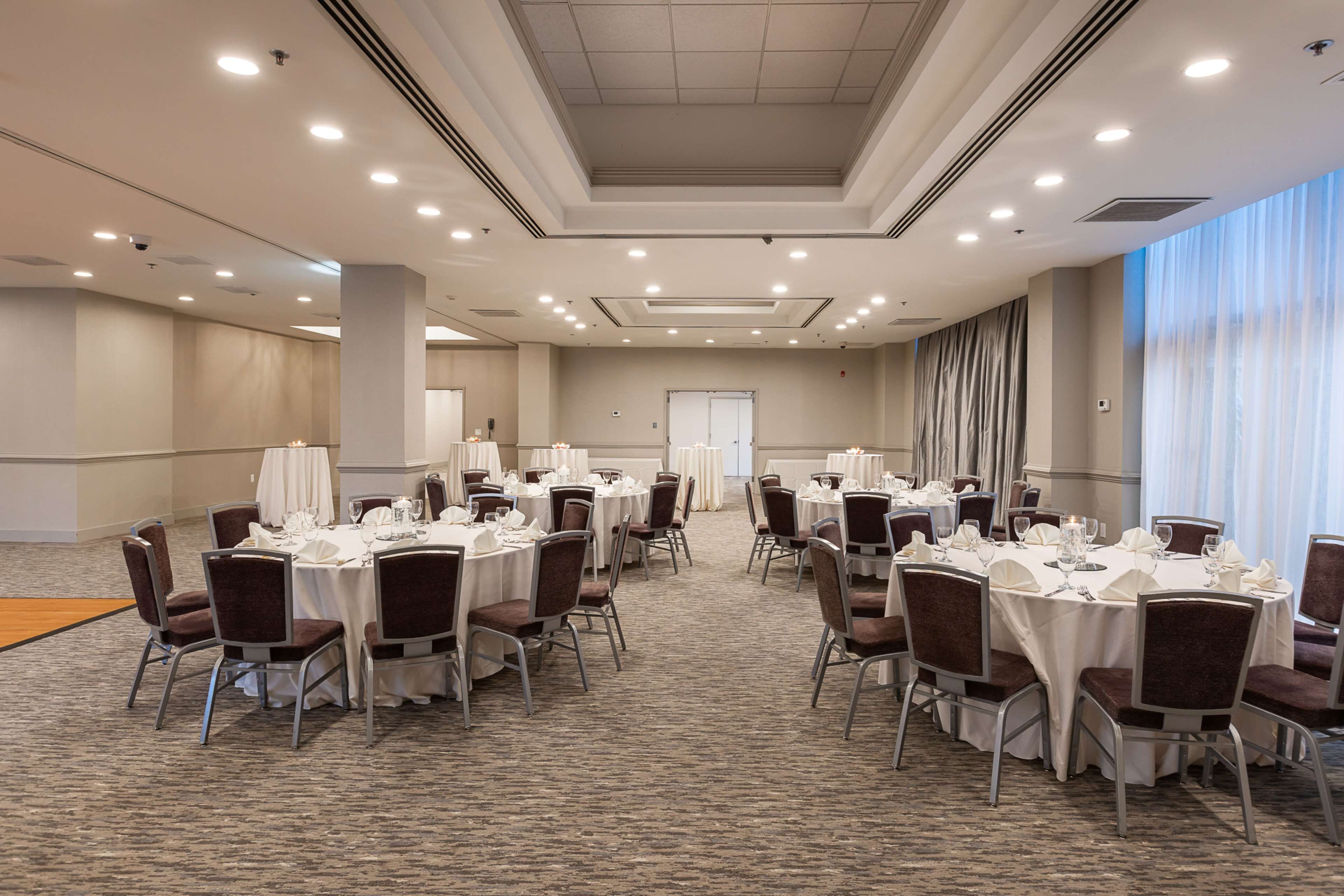 A conference room with multiple tables set for dining, equipped with chairs and table settings.