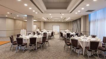 A conference room with multiple tables set for dining, equipped with chairs and table settings.