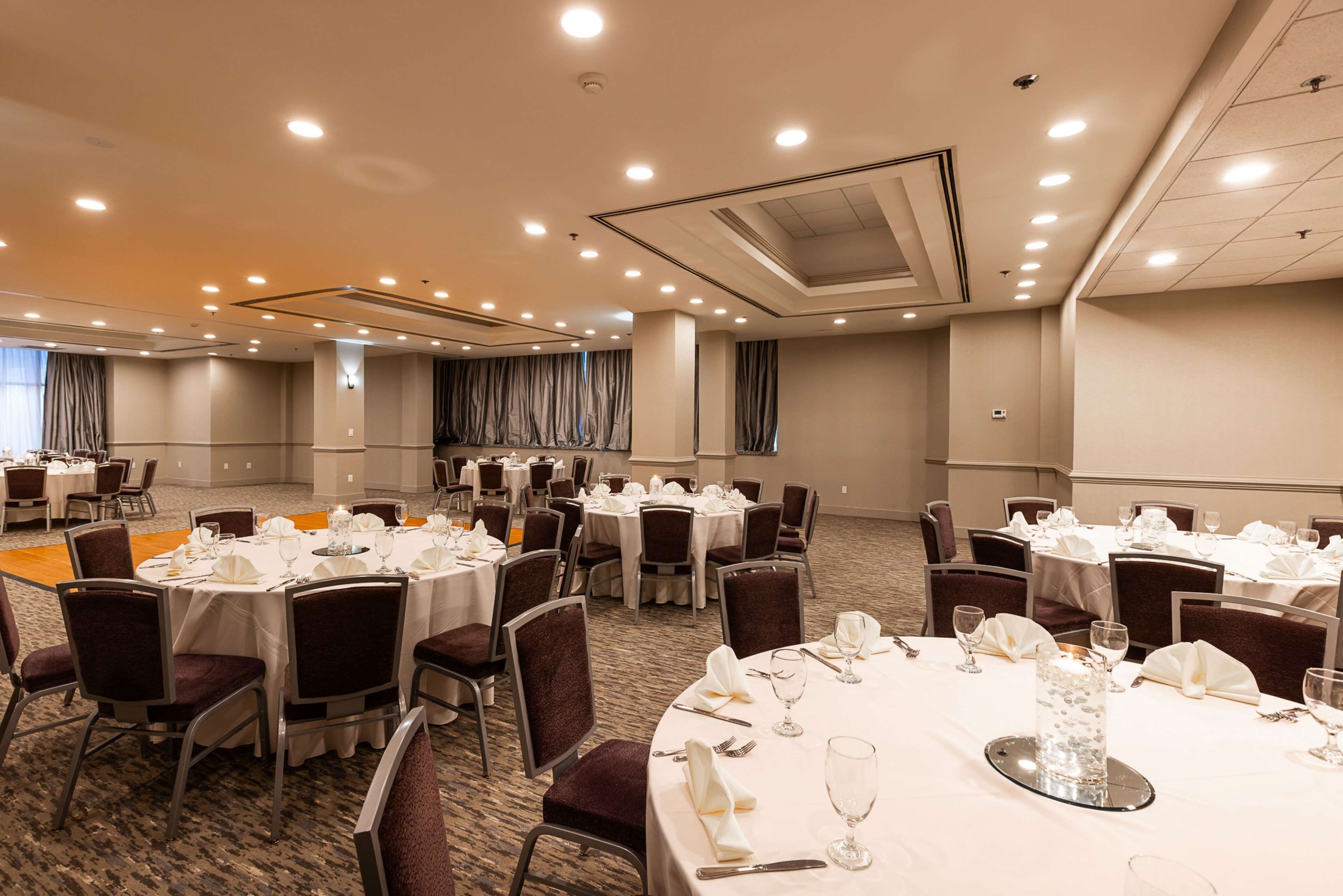 A conference room with round tables set for dining, equipped with chairs and table settings.