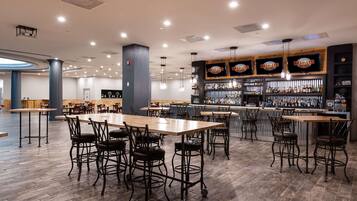 A spacious bar area with multiple seating options, a well-stocked liquor shelf, and a modern ceiling design.