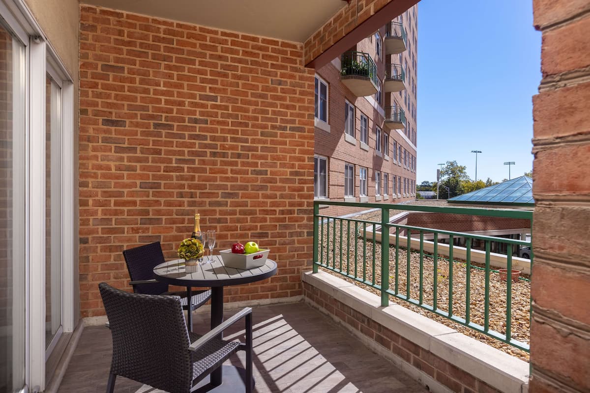 A balcony with a brick wall, a table with chairs, and a railing.