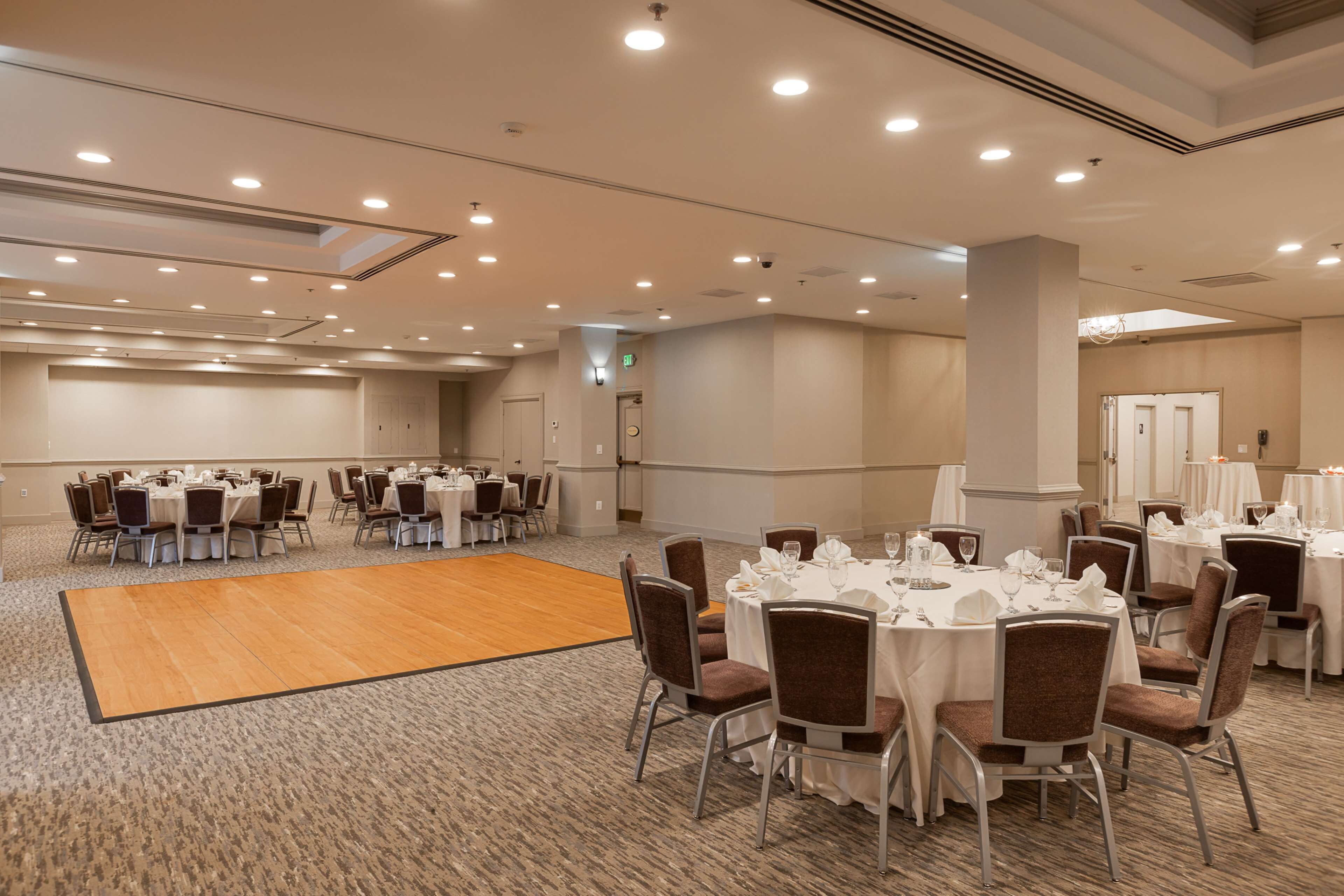 Una amplia sala de conferencias con varias mesas redondas, sillas y una zona central para baile.