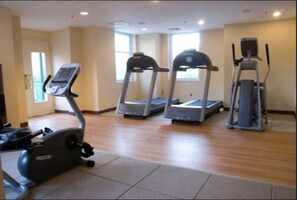Une salle de remise en forme équipée de tapis de course, d’un vélo elliptique et d’un vélo d’appartement.