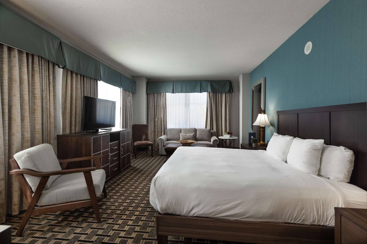 A hotel room with a large bed, a TV, a desk, and a chair.