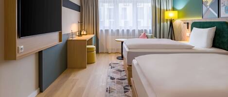 A hotel room with two beds, a desk, a TV, and a window with curtains.
