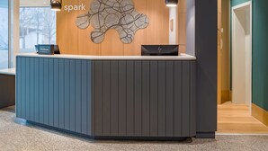 A reception desk with a modern design, a sign indicating Hilton Honors, and a decorative wall piece above it. - Spark by Hilton Stuttgart Sindelfingen (Sindelfingen)