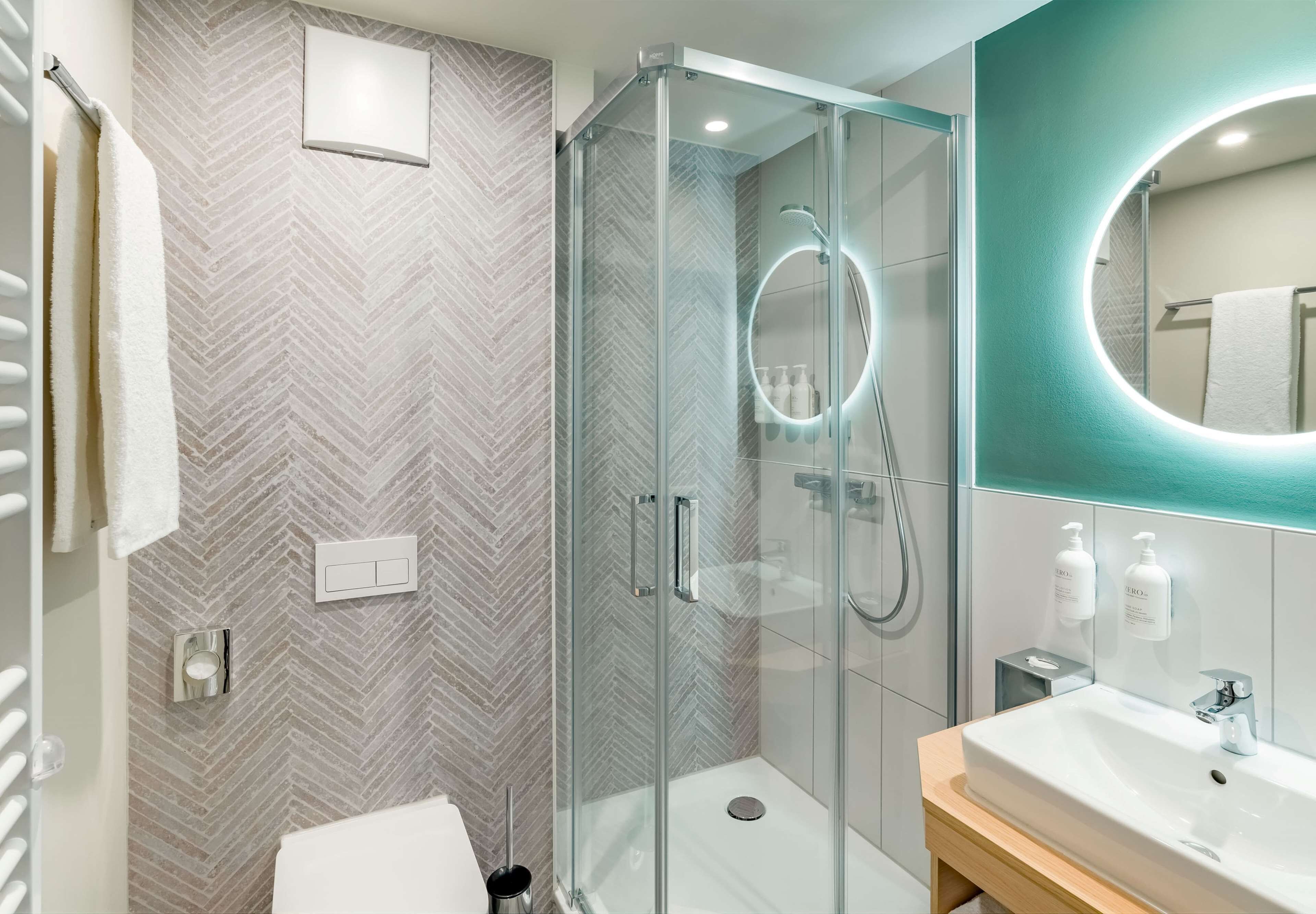 A modern bathroom with a glass-enclosed shower, a vanity with a sink, and a large mirror.