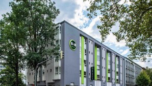 A modern hotel building with a green and grey facade, large windows, and a visible entrance. - B&B Hotel Aachen-Hbf (Aachen)
