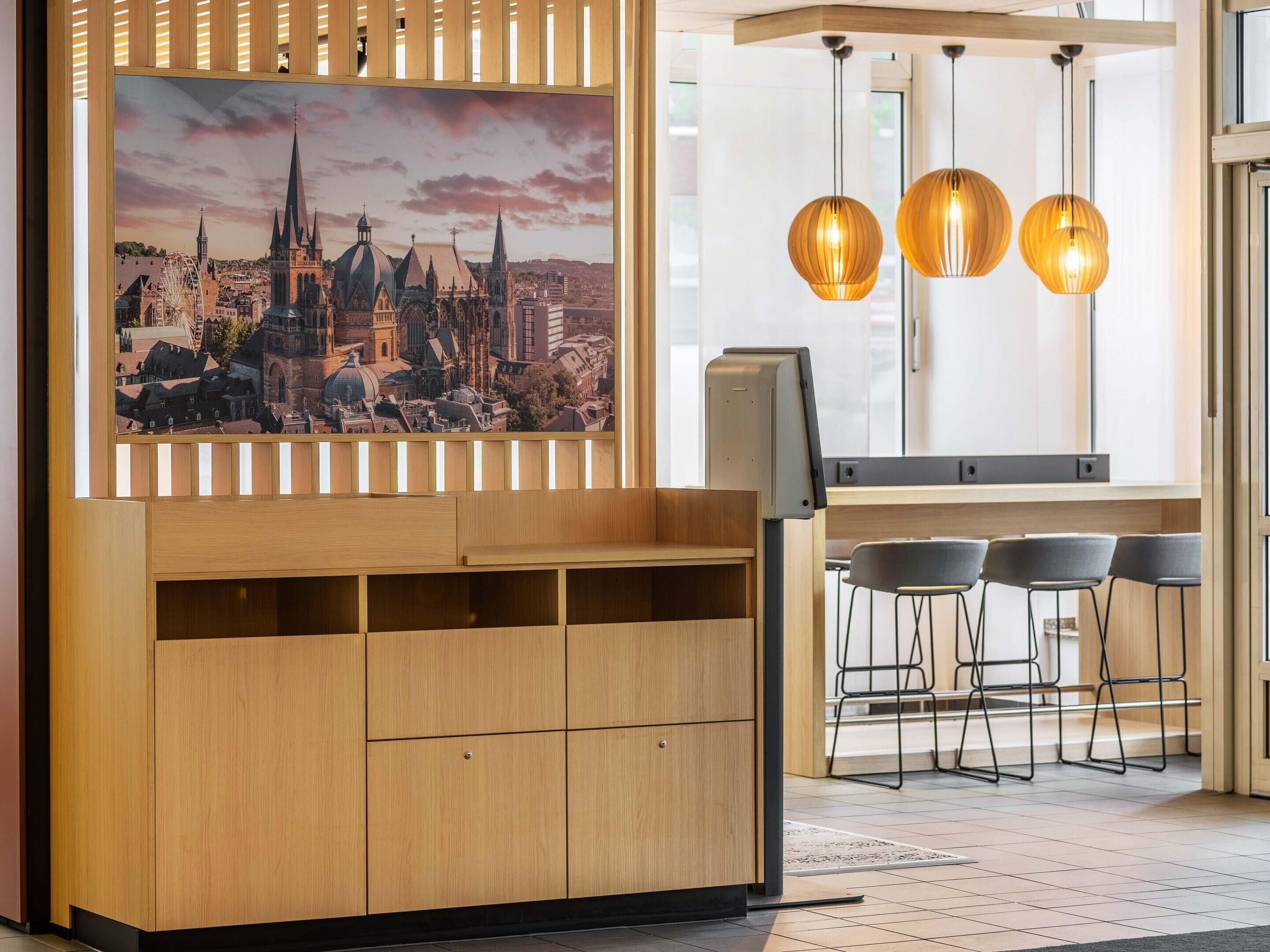 Ein modernes Interieur mit einem Holzschrank, einem Stadtbildgemälde und drei Pendelleuchten.
