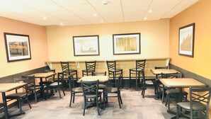 Un restaurant avec de nombreuses tables et chaises, des tableaux encadrés aux murs et un sol à motifs.