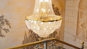 Una imponente escalera con un candelabro de cristal, murales ornamentales y un diseño arquitectónico clásico.