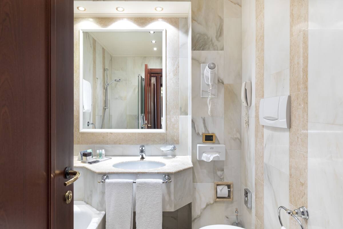 Une salle de bain équipée d’un lavabo, d’un miroir, d’un porte-serviettes et d’une douche.