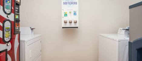 A laundry facility with a sign for soap, bleach, and softeners, and a vending machine with various products.