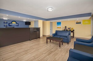 Uma área de recepção com balcão, um sofá azul e um espaço para café.