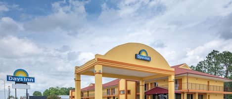 A Days Inn hotel with a yellow exterior, a covered parking area, and a sign with the Days Inn logo.