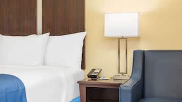 Una habitación de hotel con una cama, un escritorio con lámpara y una silla.