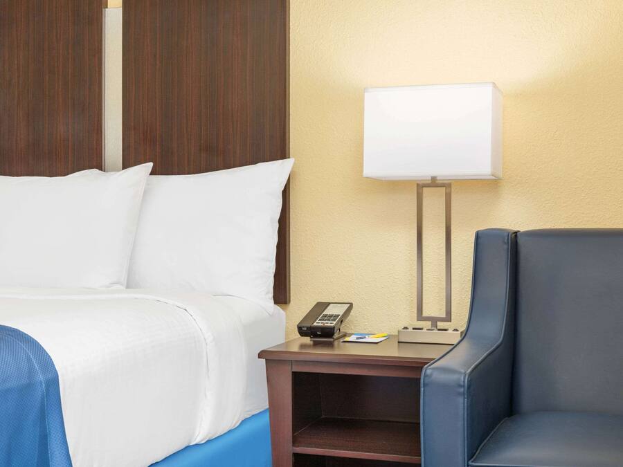 Una habitación de hotel con una cama, un escritorio con lámpara y una silla.