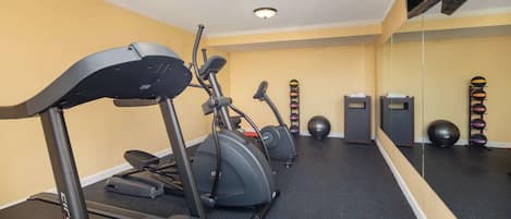 A gym with treadmills, elliptical machines, and exercise balls.