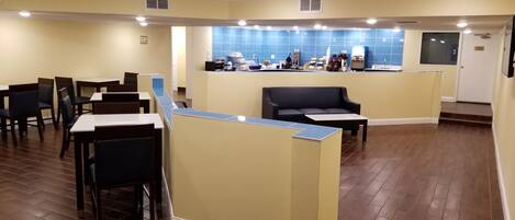 A restaurant with booths and tables, a counter with a blue tiled backsplash, and a door in the background.