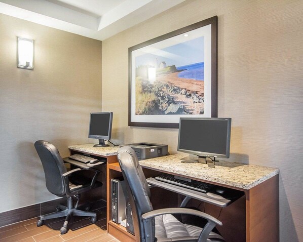 Una habitación de hotel con un escritorio, dos monitores, un teclado y dos sillas.