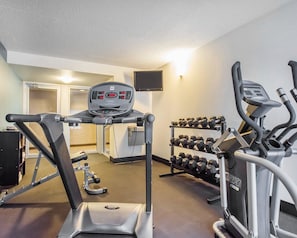 Un gimnasio con cintas de correr, mancuernas y una bicicleta estática.